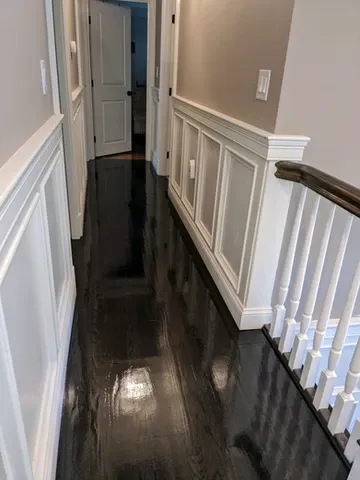 Hallway with dark reflective floors and white wainscoting