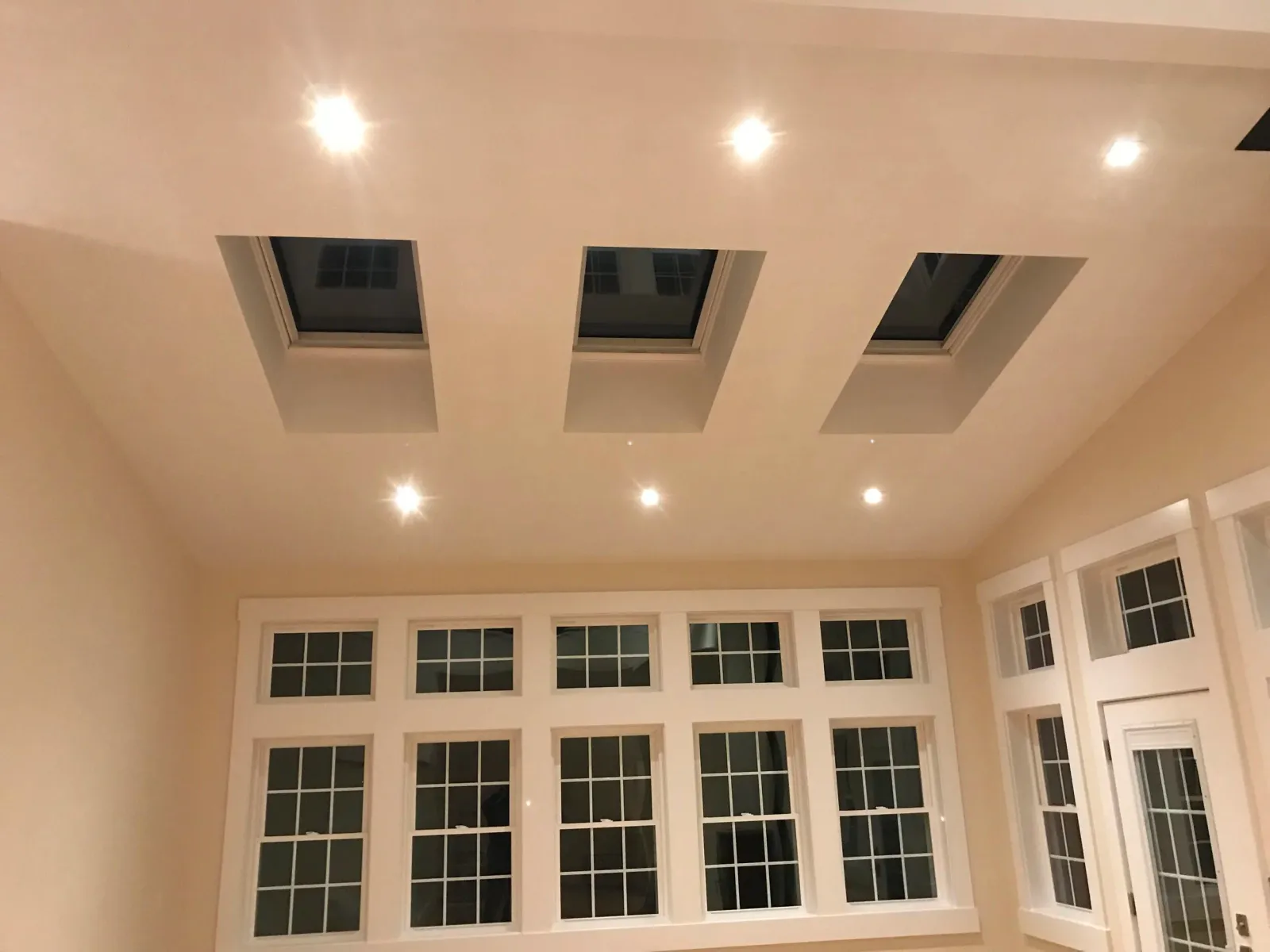 Room interior with skylights, recessed lighting, and large windows