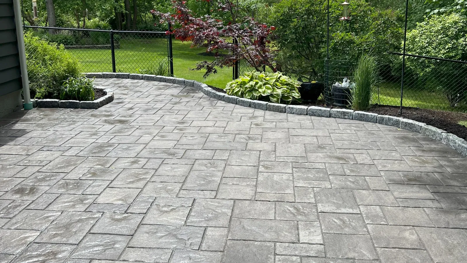 Paver patio installation in Lynnfield, MA by Goodwood General Construction featuring Andover Collection™ StoneCleft pavers and granite cobble edging for a classic New England look