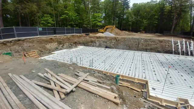 A large hole in the ground is being filled with concrete.