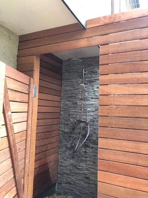 Outdoor shower enclosure with stone and cedar surround