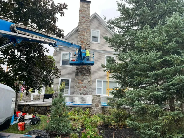 A man is cleaning a chimney on the side of a house