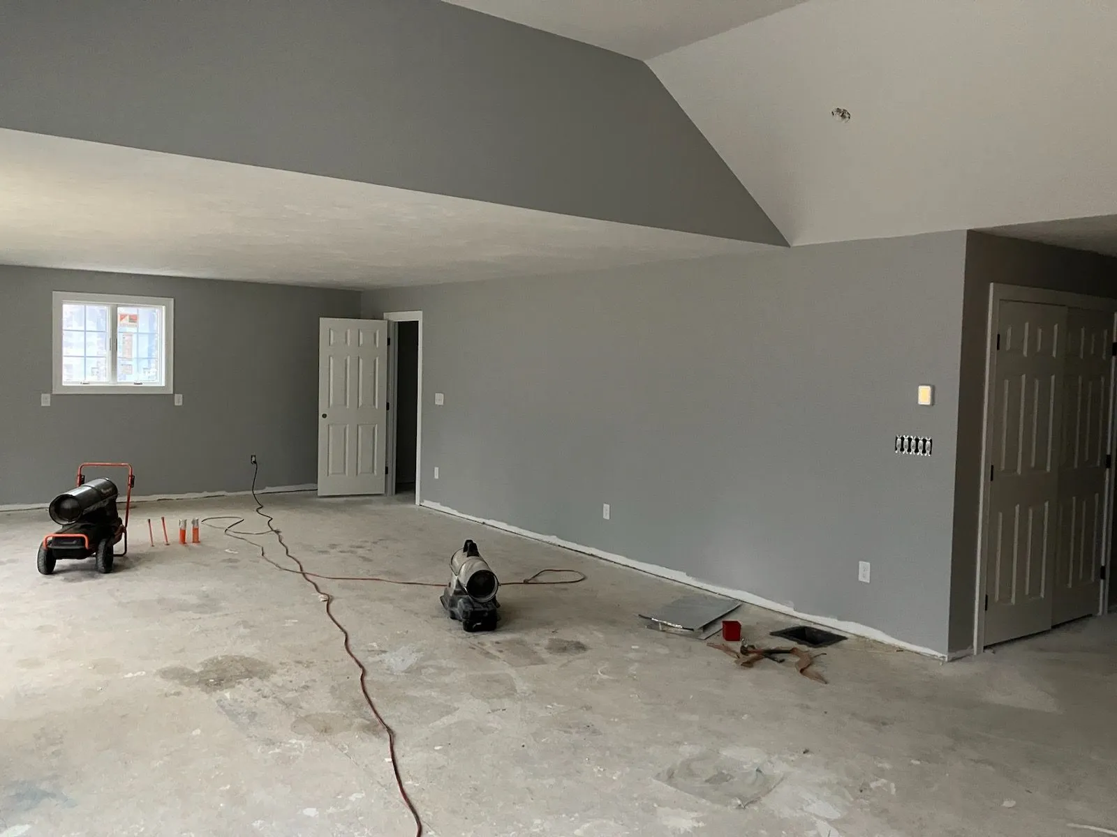 A large empty room with a vaulted ceiling and gray walls.