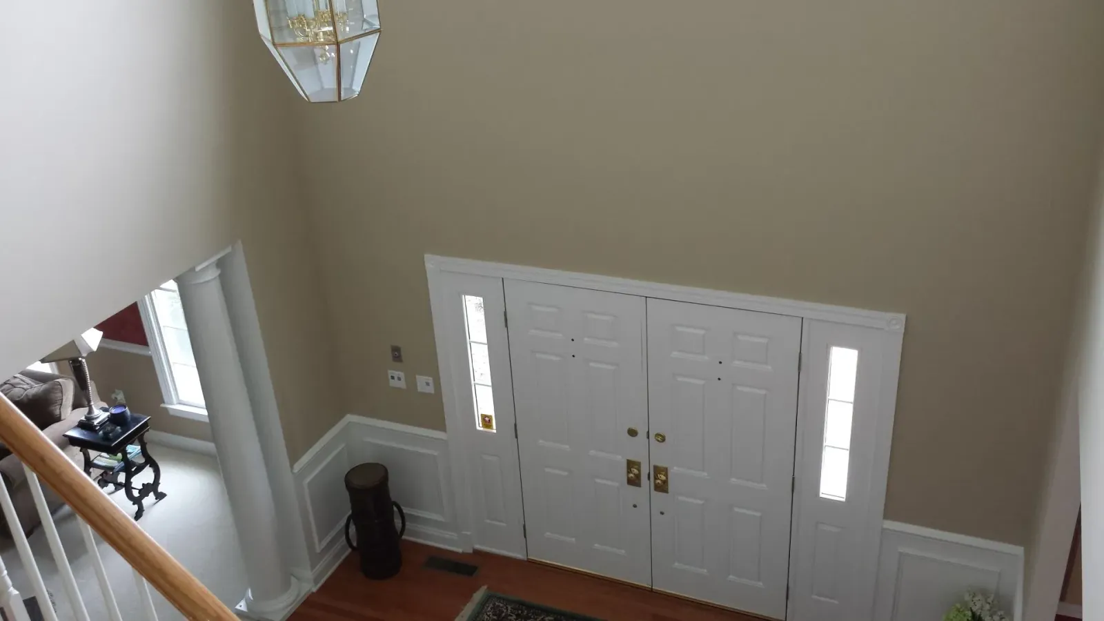 Overhead view of a home entryway with double doors, sidelights, and a chandelier; tan walls, hardwood floor.