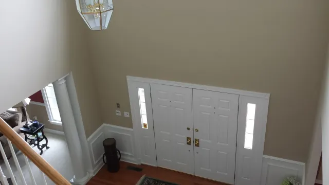 Overhead view of a home entryway with double doors, sidelights, and a chandelier; tan walls, hardwood floor.