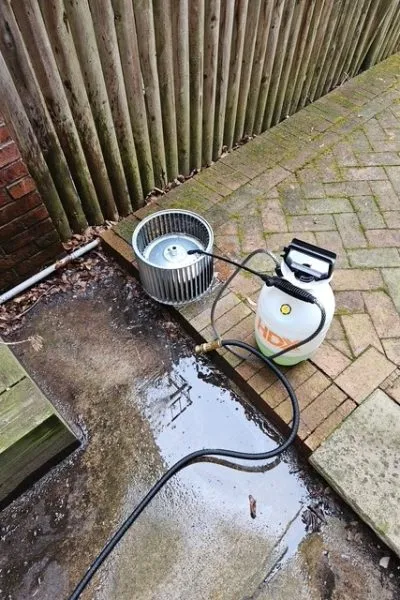 Garden sprayer and metal fan beside puddle