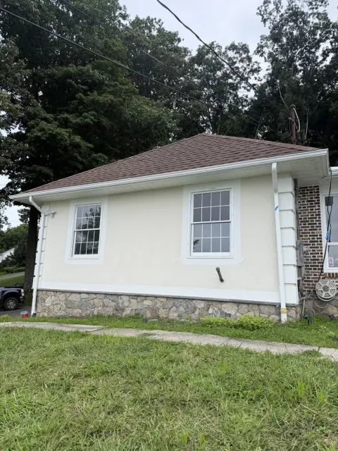 Stone veneer foundation band along the side of a stucco home