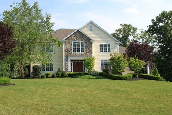 Custom home with stone-veneer turret and mature plantings