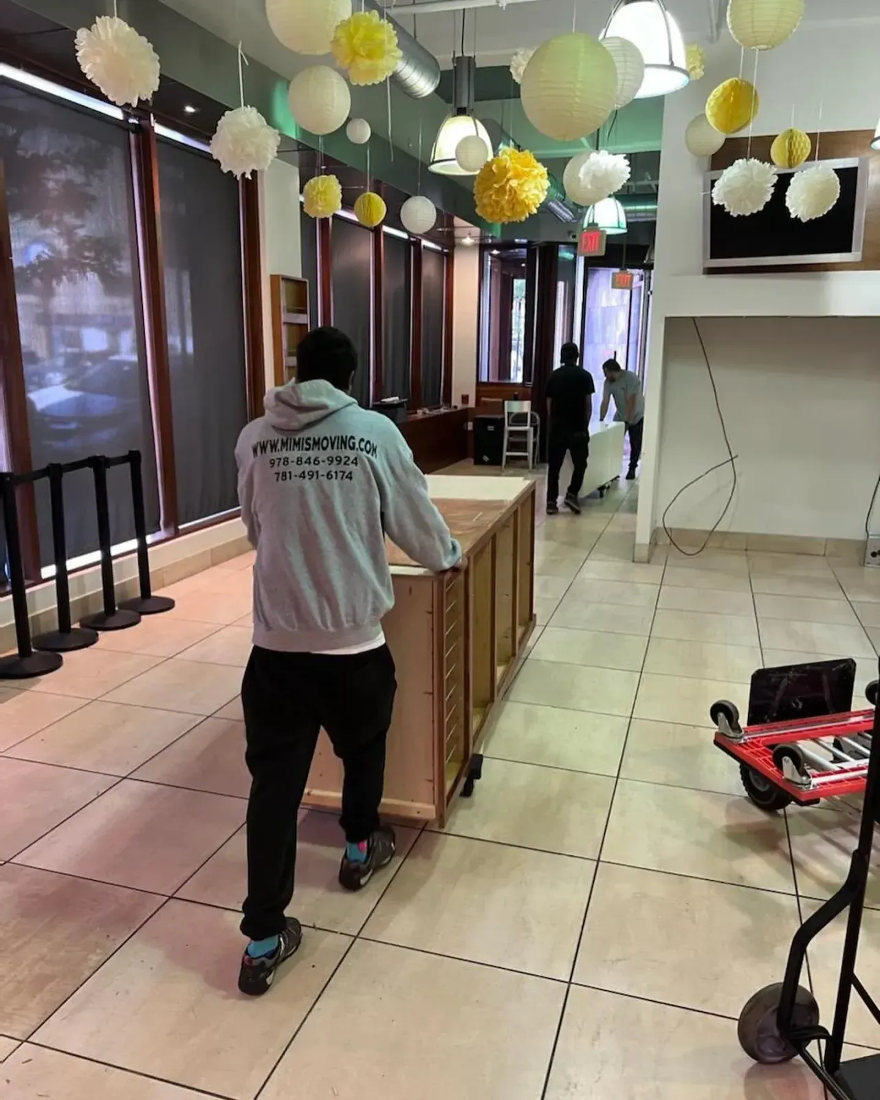 People moving a large cabinet in a store with decorations.
