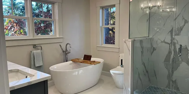 High-end master bathroom renovation in Natick MA featuring freestanding tub, large glass shower, and marble tiling