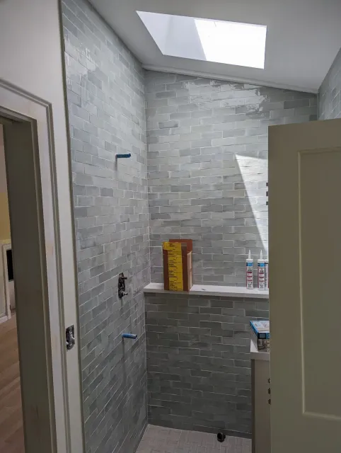 A bathroom with a walk in shower and a skylight.