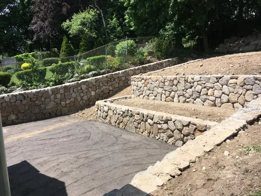 Stone terraced steps and retaining walls beside a paved path in a landscaped park
