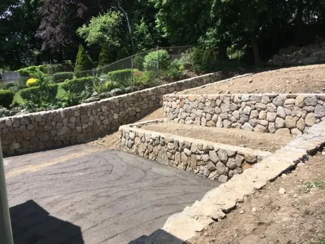 Stone terraced steps and retaining walls beside a paved path in a landscaped park