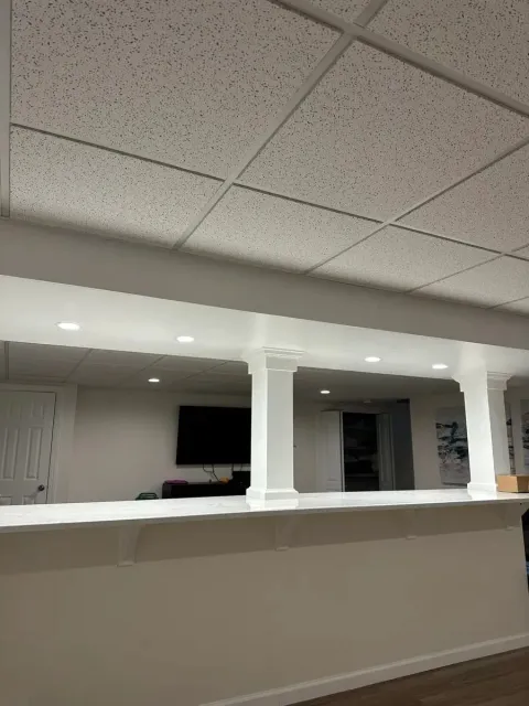 Empty office reception area with white columns, beige counter, and drop ceiling.