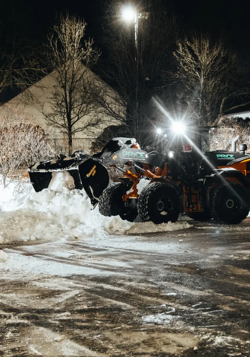 Price Landscape and Construction onsite at a business parking lot removing snow with a loader machine