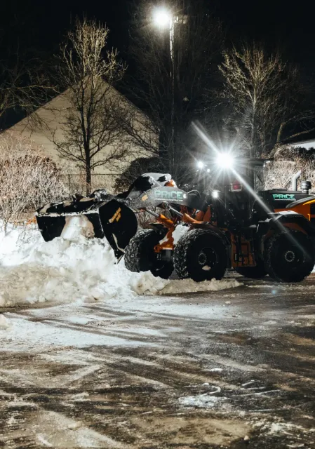 Price Landscape and Construction onsite at a business parking lot removing snow with a loader machine