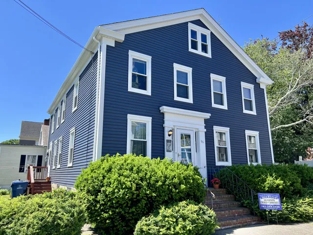 Two-and-a-half-story New Bedford, MA Greek Revival colonial clad in new Exterior Portfolio Market Square Indigo vinyl siding with white trim, corner pilasters, an entablature front door, and granite entry steps