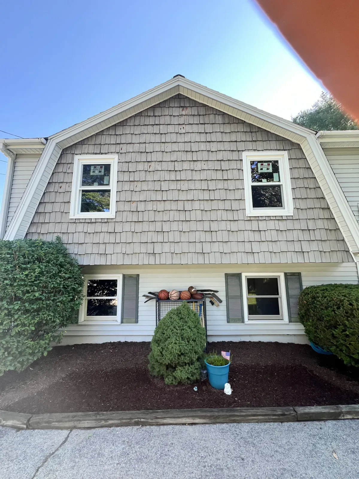 Gambrel roof home re-sided in cedar-tone shingles