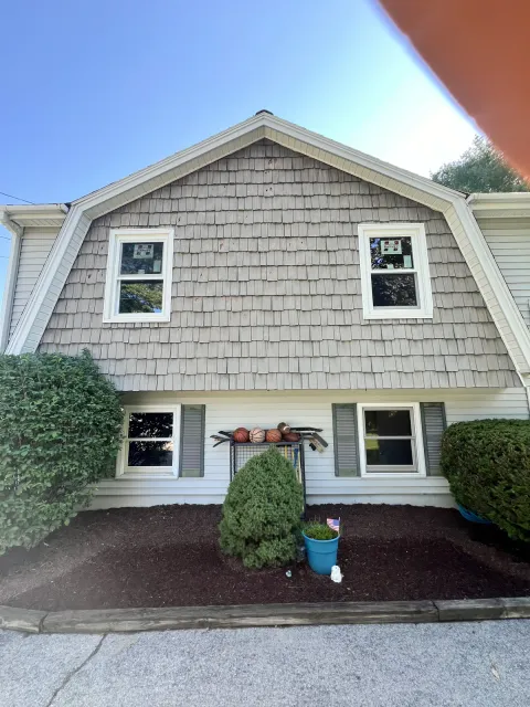 Gambrel roof home re-sided in cedar-tone shingles