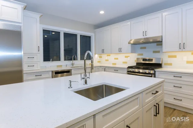 Completed white kitchen with quartz island and stainless appliances