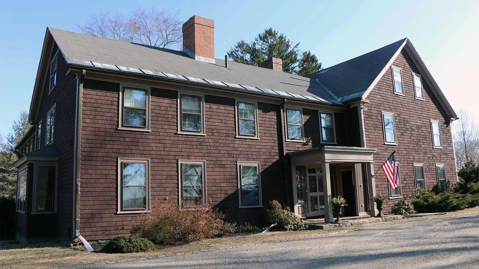 Image features the front of an antique recently re-sided using pre-stained shingles.