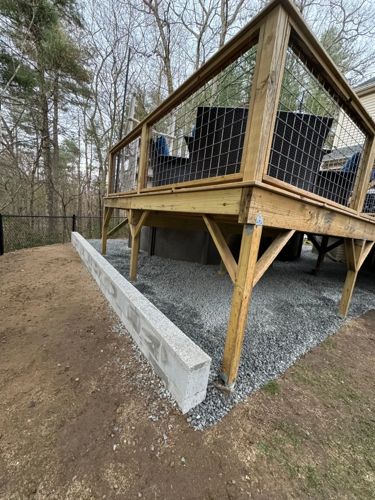 A wooden deck with a couch and chairs on it in the woods.