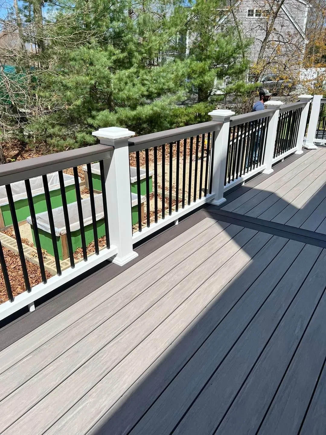 A wooden deck with a white railing and trees in the background