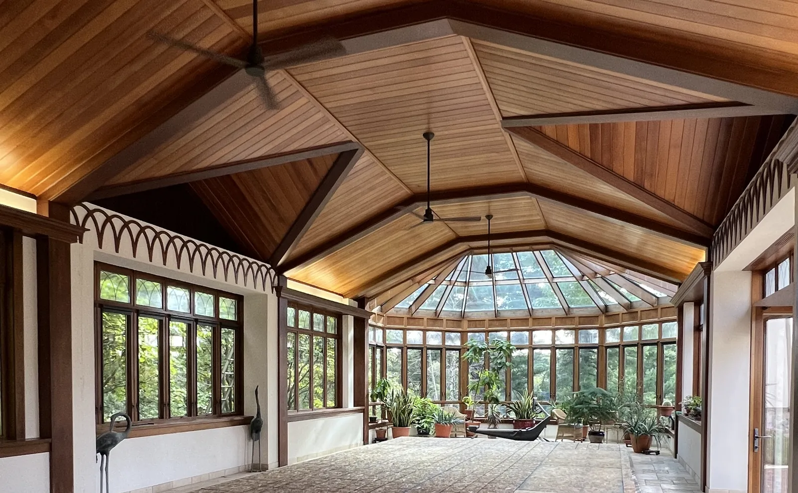 Rustic conservatory with exposed wood beams, vaulted ceiling and abundant plants