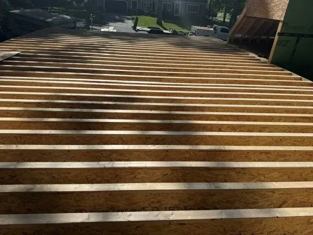 Wooden boardwalk with horizontal slats leading through a park in bright sunlight