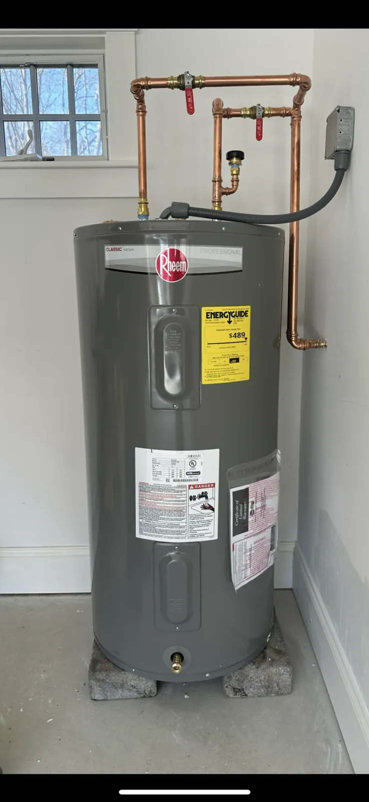 A water heater is sitting in a room next to a window.