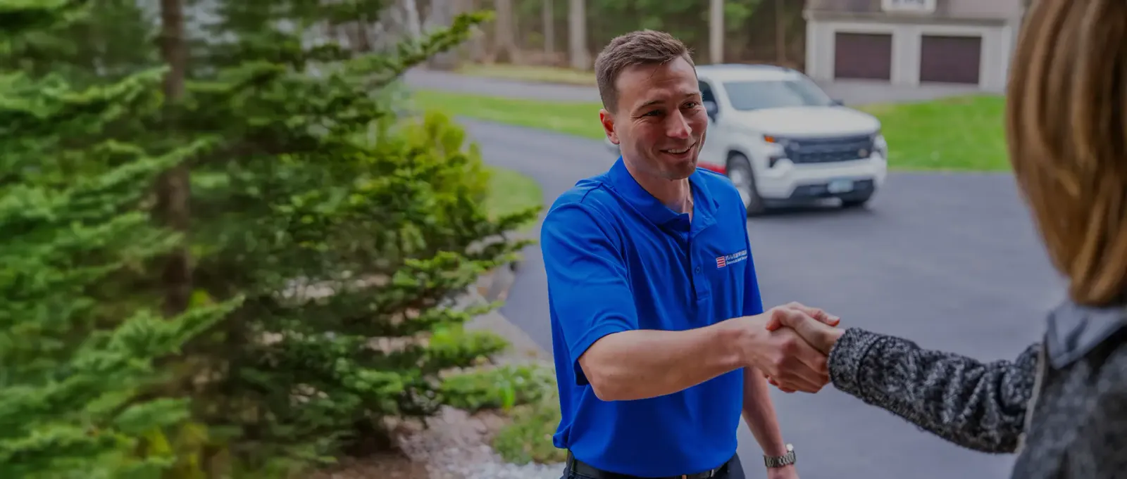 A Door Systems employee shakes hands outdoors with a woman.