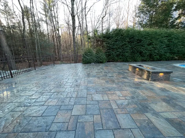 A patio with a bench and trees in the background.