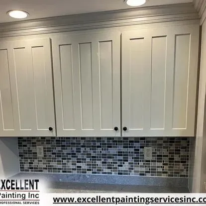 A kitchen with white cabinets and a tile wall.