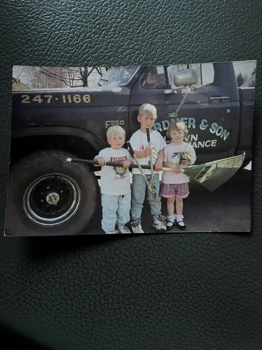 Three third-generation Gardner children standing with lawn-care tools in front of the family’s original Gardner and Son truck