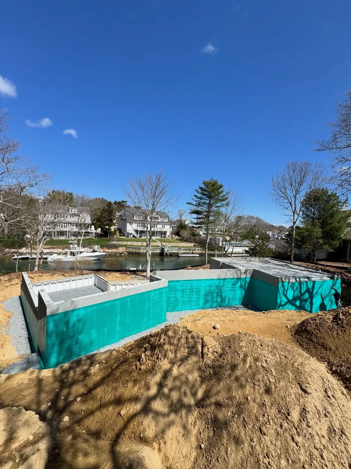 Foundation walls waterproofed with a teal membrane on a coastal job site