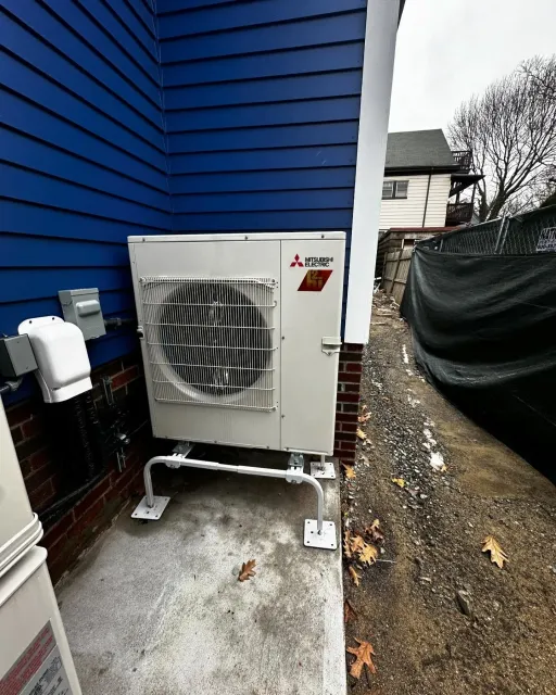 a white air conditioner is sitting on the side of a blue house