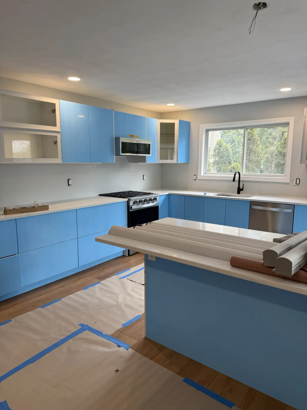 Glossy white Salem kitchen cabinetry protected by blue installation film during final installation