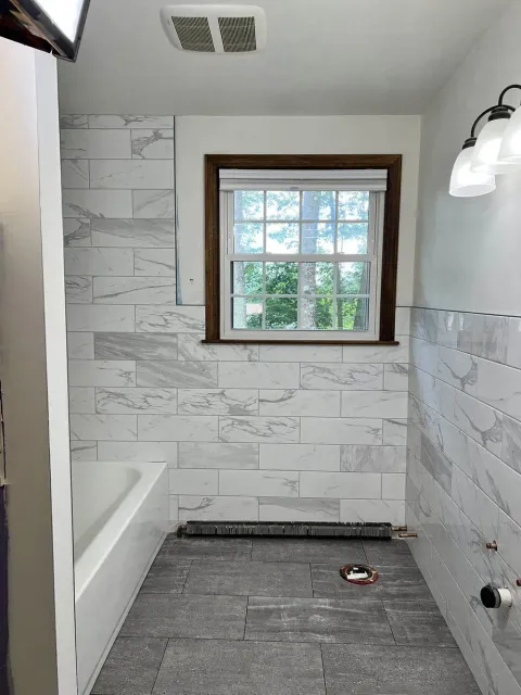 A bathroom with white tiles and a window.