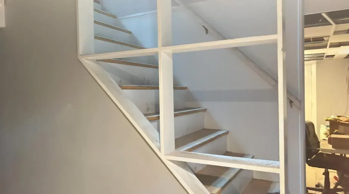 A staircase with a shelf between the steps in a room.