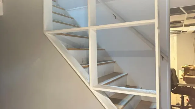 A staircase with a shelf between the steps in a room.