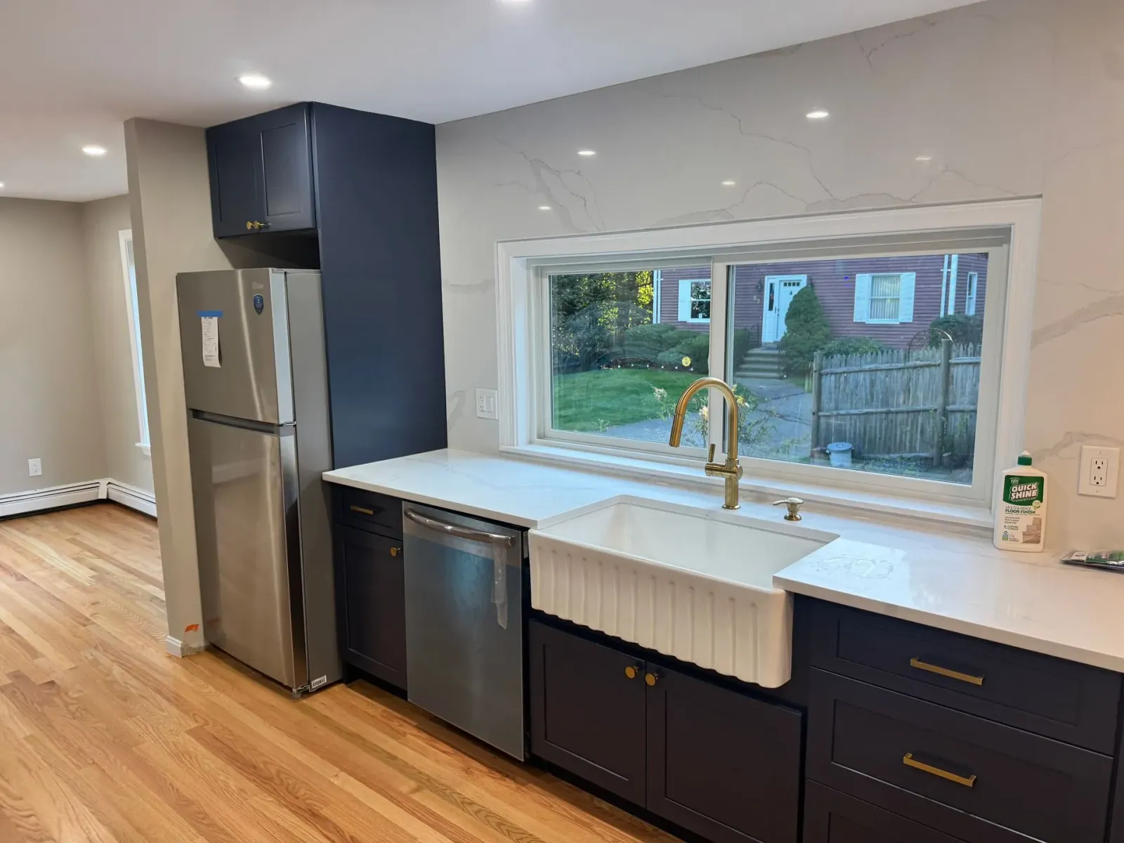 Modern kitchen with navy cabinets, stainless steel appliances, white countertops, and a farmhouse sink.