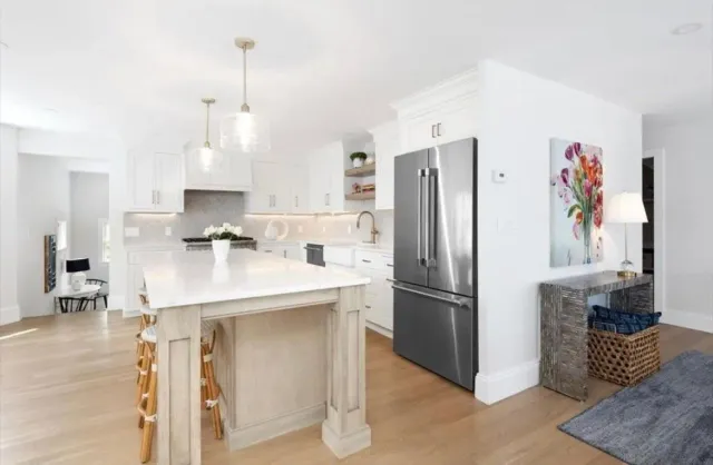 A kitchen with a large island and a stainless steel refrigerator.