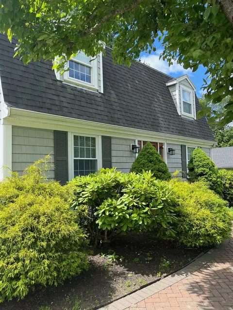 Roof, gutters, and exterior trim renewal on a Wakefield colonial revival. Crew on-roof during finish photo.