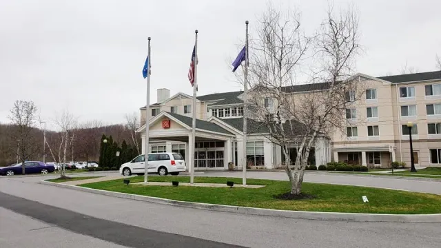 A white van is parked in front of a large building.