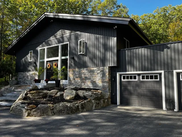 Modern exterior renovation featuring black siding and stone veneer on a New Hampshire home.