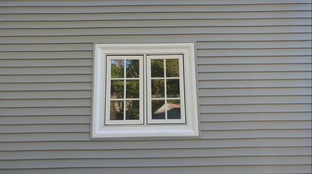 A white window is on the side of a house.