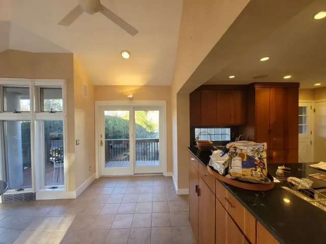 Spacious kitchen with dark countertops, tiled floor, and glass doors leading to a patio.