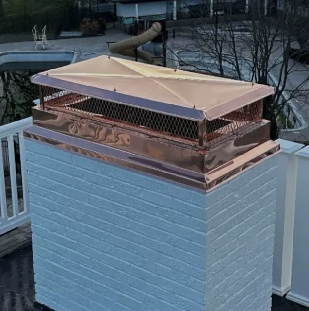 New custom copper chase cover and mesh spark arrestor on a light masonry chimney beside a backyard pool