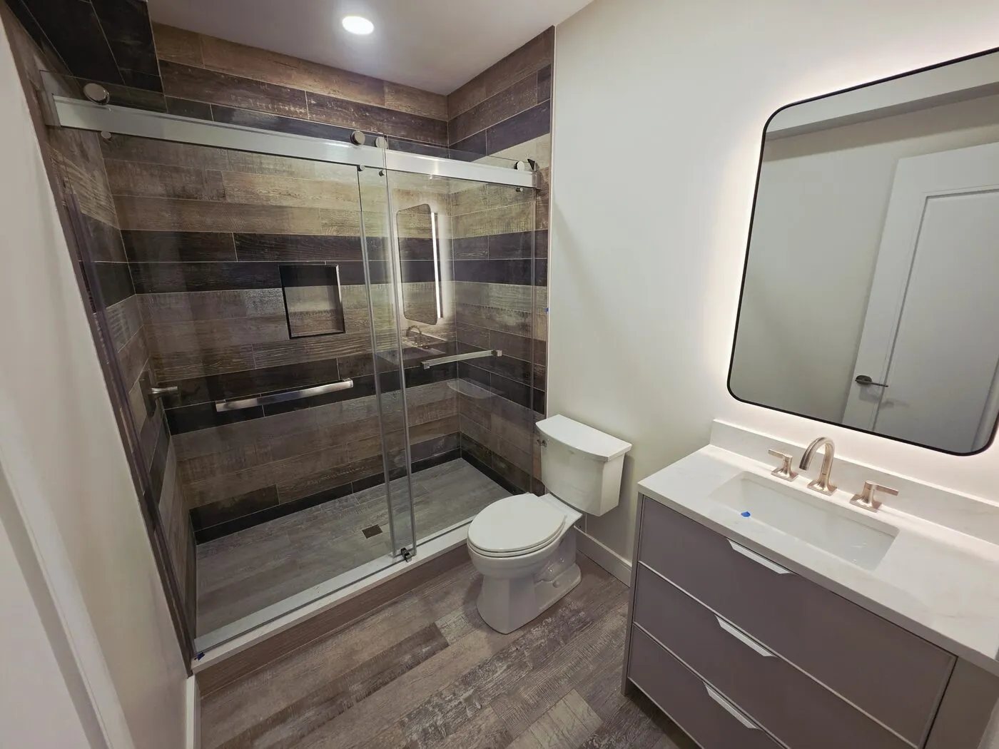 Bathroom remodel with wood-look porcelain tile, frameless glass shower and floating vanity
