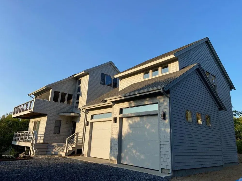 Modern gray house with garage and balconies under a clear blue sky
